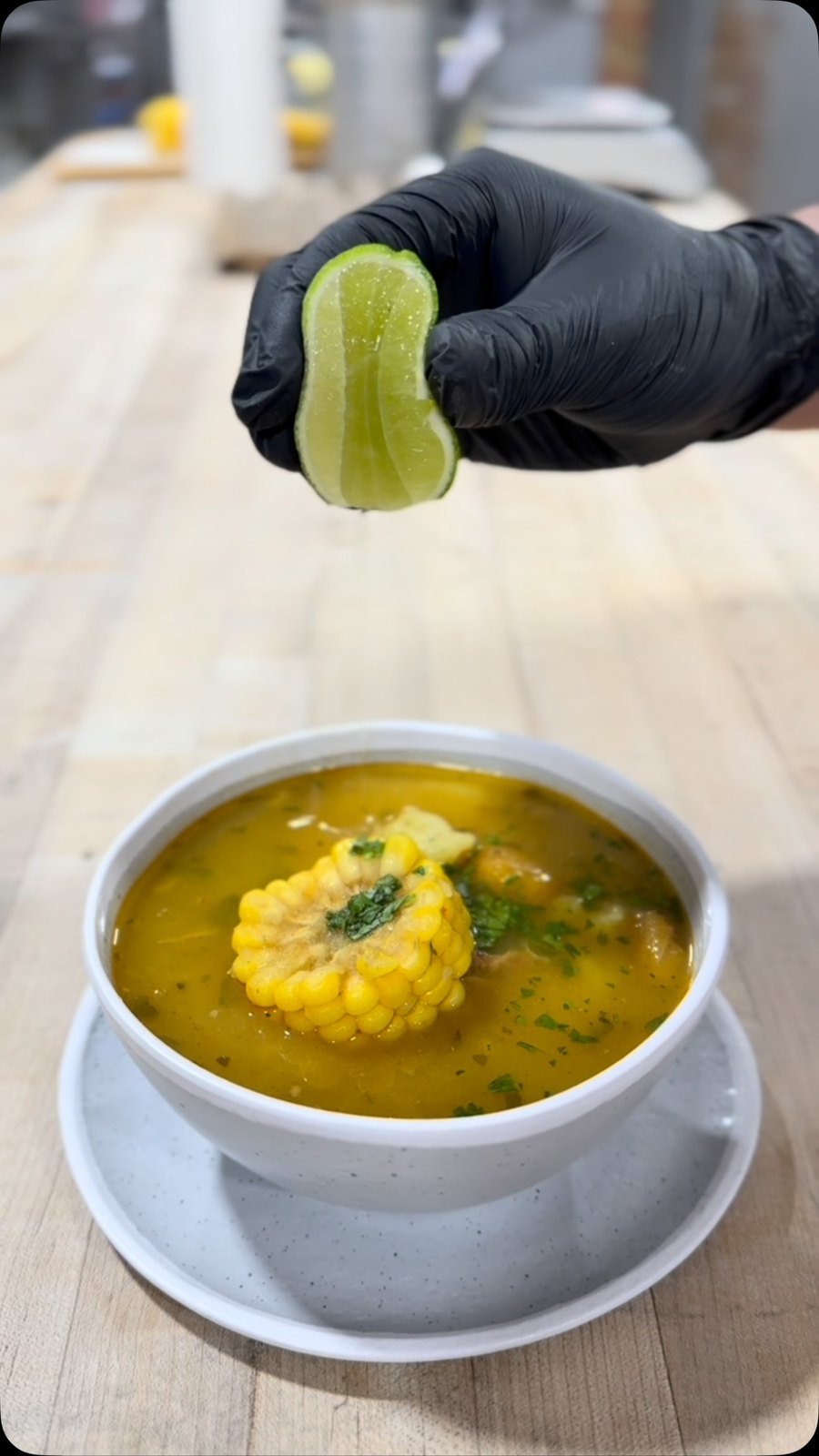 A bowl of Colombian sancocho with corn and a squeeze of lime