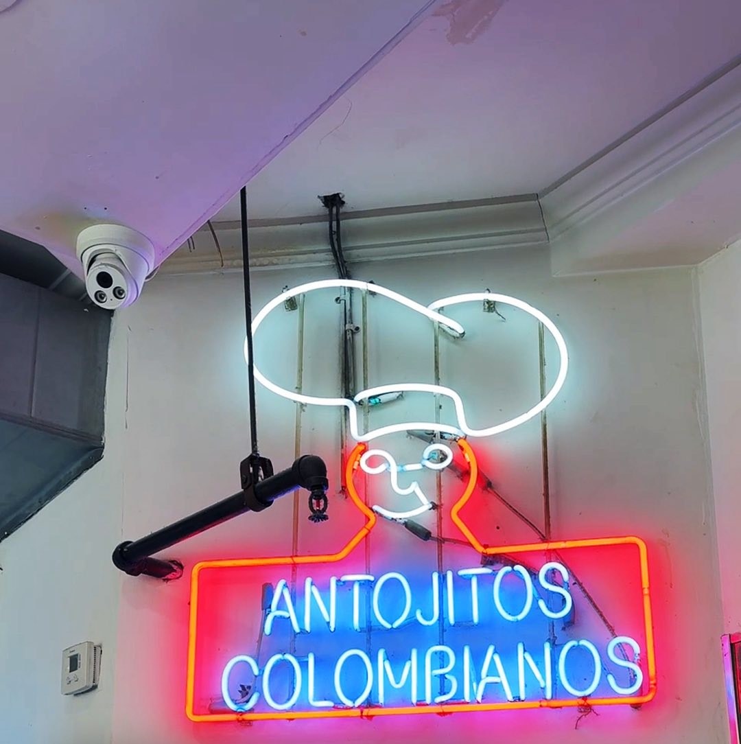 The in-store neon chef sign over 'Antojitos Colombianos' at Seba Seba