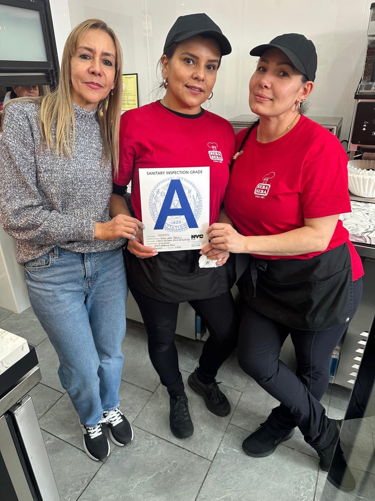 Seba Seba counter team in red logo shirts holding the NYC Grade A card